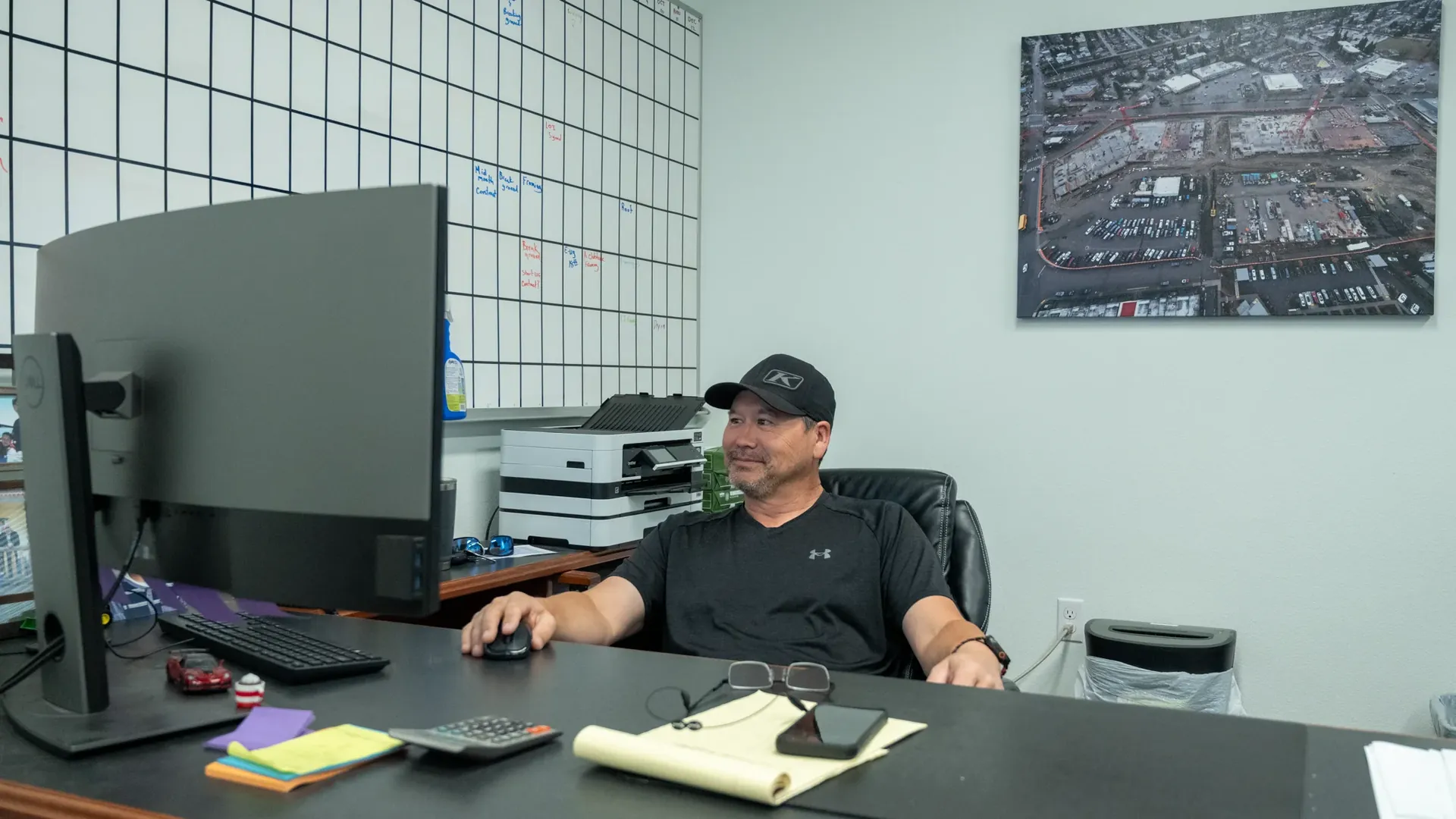 Edison team member at his workstation beneath an aerial project photo